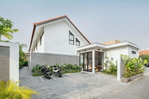 Une maison moderne à deux étages, dotée d’un patio couvert et d’un petit jardin.