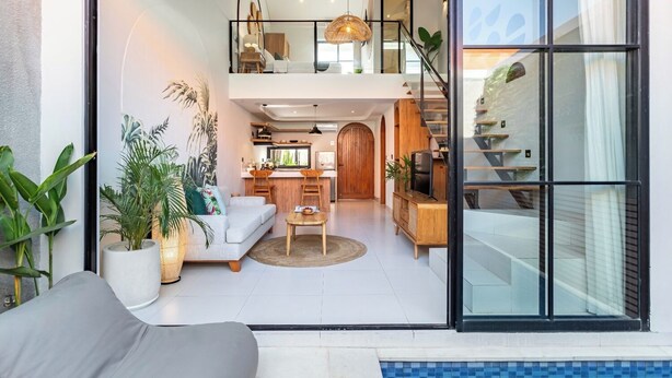 A modern apartment with a living room, dining area, kitchen, and a staircase leading to an upper level. - Cove Anantaha Loft & Villa (Keroboken Kelod)