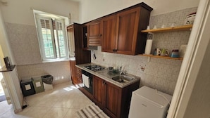 A kitchen with wooden cabinets, a stove, a sink, and a refrigerator. - House with a view of Lake Nemi  (Genzano di Roma)