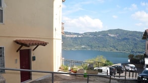 A building with a red door and a balcony overlooking a lake and hills. - House with a view of Lake Nemi  (Genzano di Roma)