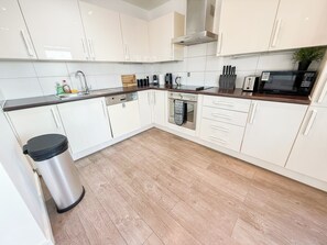 A modern kitchen with white cabinets, a stainless steel dishwasher, an oven, and a microwave. - Hoxton 3Bedroom Penthouse w/ Balcony & Lift near Shoreditch, Hackney, Old Street (London)