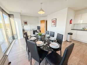 A modern dining area with a glass table, black chairs, and a view of the outdoors. - Hoxton 3Bedroom Penthouse w/ Balcony & Lift near Shoreditch, Hackney, Old Street (London)