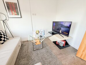 A living room with a flat-screen TV, a glass coffee table, a sofa, and a carpeted floor. - Hoxton 3Bedroom Penthouse w/ Balcony & Lift near Shoreditch, Hackney, Old Street (London)