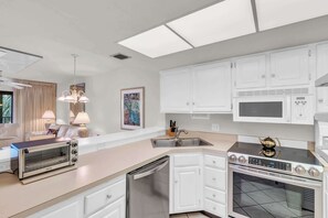 A modern kitchen with white cabinets, a built-in microwave, a stove, and a dishwasher.