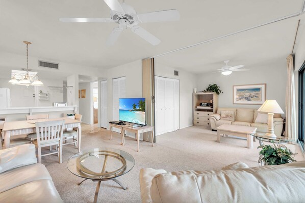 Una sala de estar amplia con televisor, zona de estar y mesa de comedor.