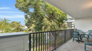 A balcony with a view of trees and a building in the background. - G-244 - Resort and Pool Views & Sleeps 4 (Naples)