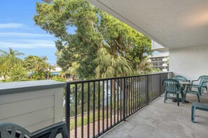 A balcony with a view of trees and a building in the background. - G-244 - Resort and Pool Views & Sleeps 4 (Naples)