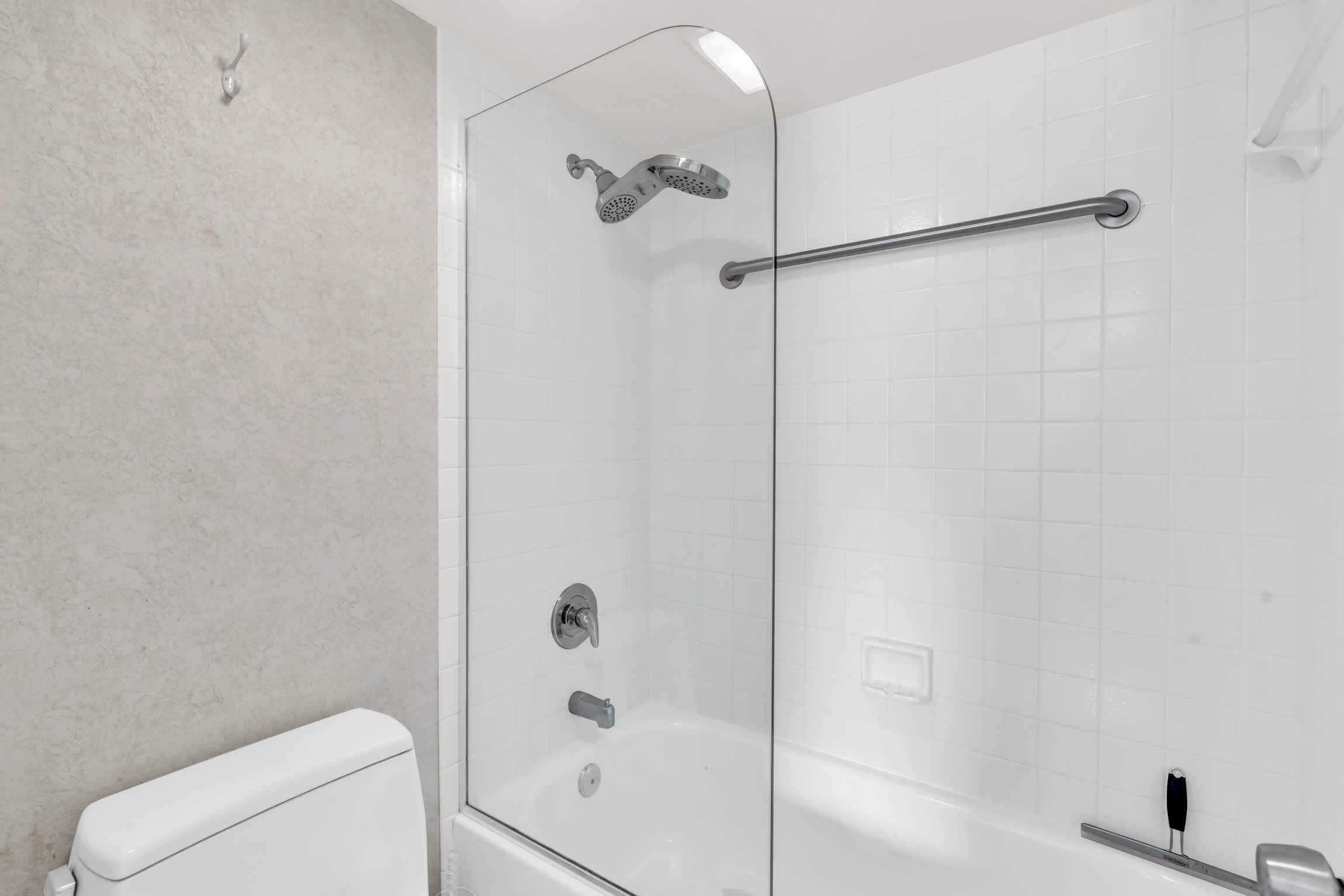 A modern bathroom with a glass-enclosed shower, a glass door, a white toilet, and a bathtub.