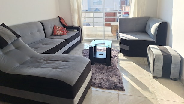 Ein modernes Wohnzimmer mit einem grauen Sofa, einem schwarzen Sessel und einem kleinen Couchtisch.
