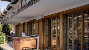 A wooden building with large windows and a hot tub outside. - Lush Apartment With Sauna and hot tub (Saanen)