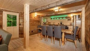A wooden interior with a dining area featuring a table and chairs, a kitchen with a green-lit bar, and a door with a window. - Chalet in Gstaad Near Ski Slopes (Rossiniere)