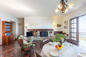 A dining area with a fireplace, wooden furniture, and a view of the outdoors. - Lago Azzurro Infinity View (Premeno)