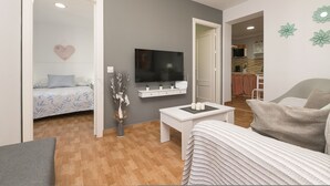 A modern living room with a bed, a TV, a coffee table, and a sofa.