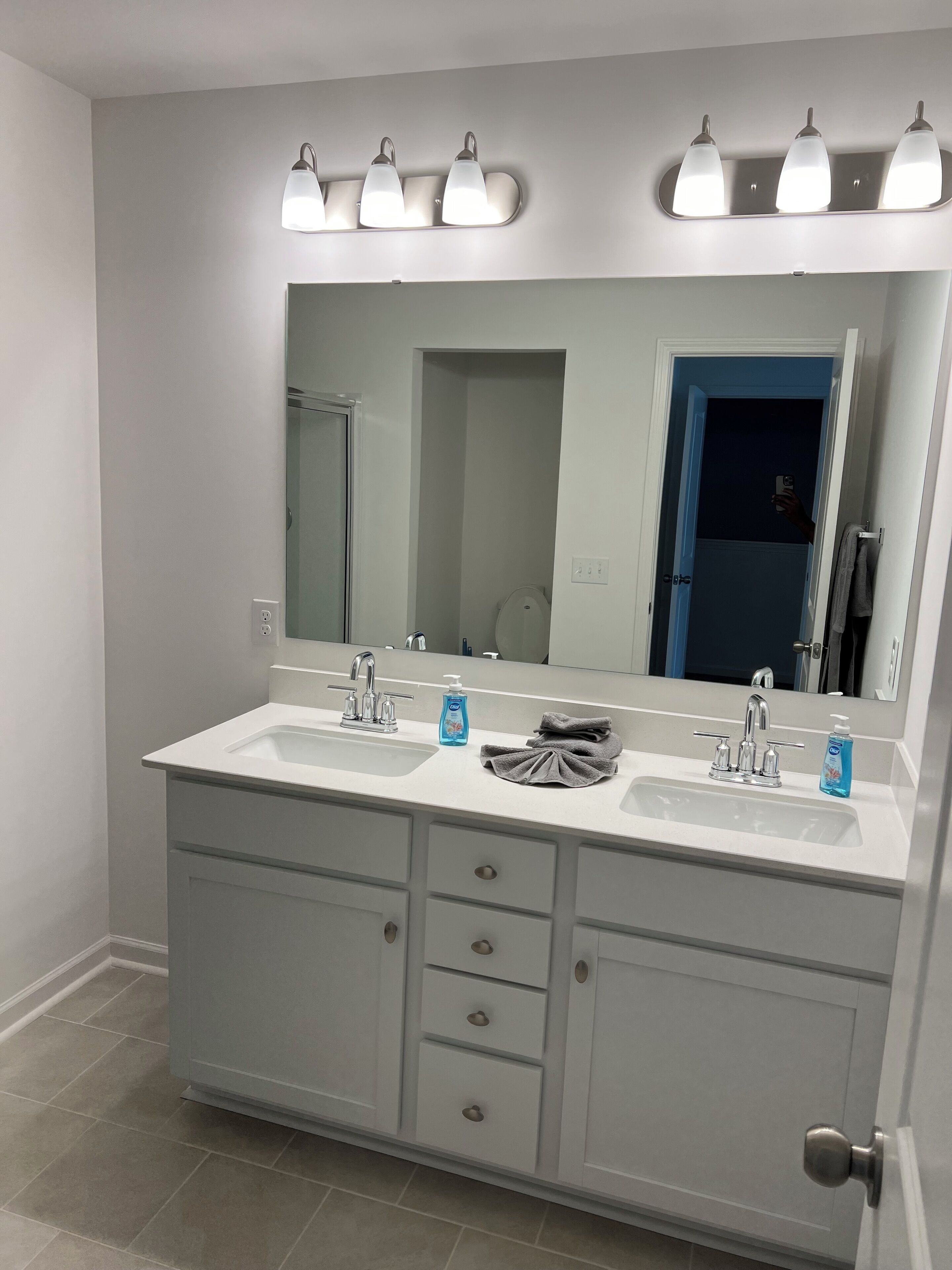 A bathroom with a double sink vanity, a large mirror, and a towel rack.
