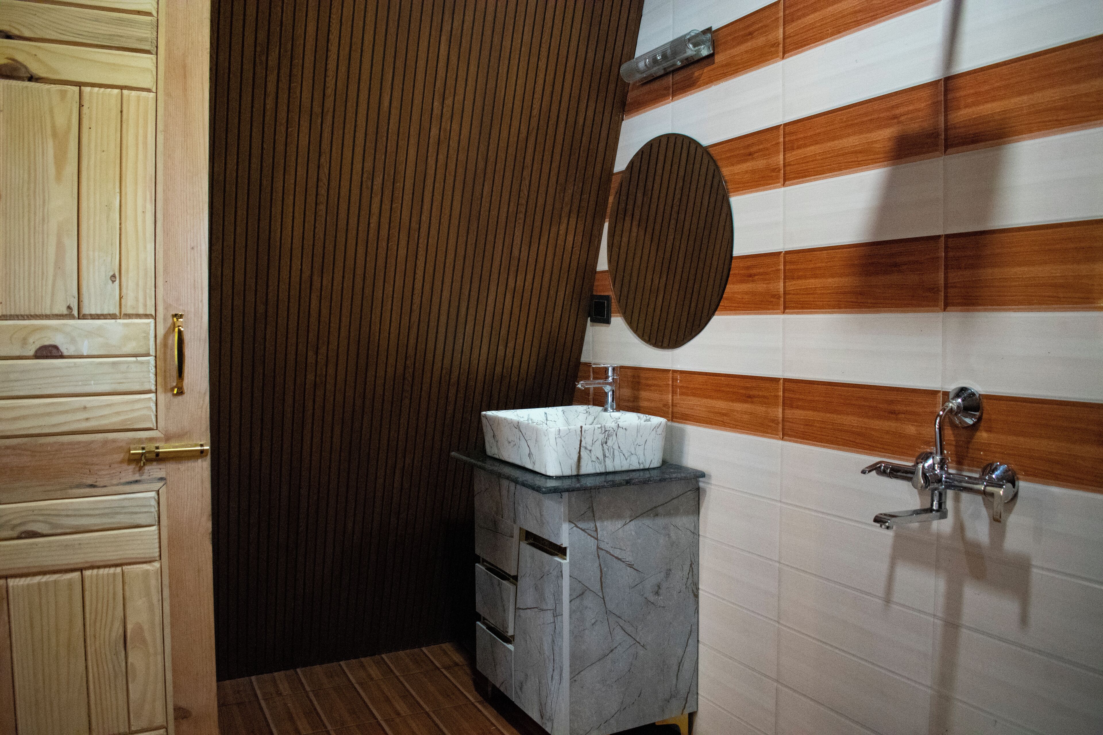 A bathroom with a wooden door, a marble sink, and a mirror on the wall.