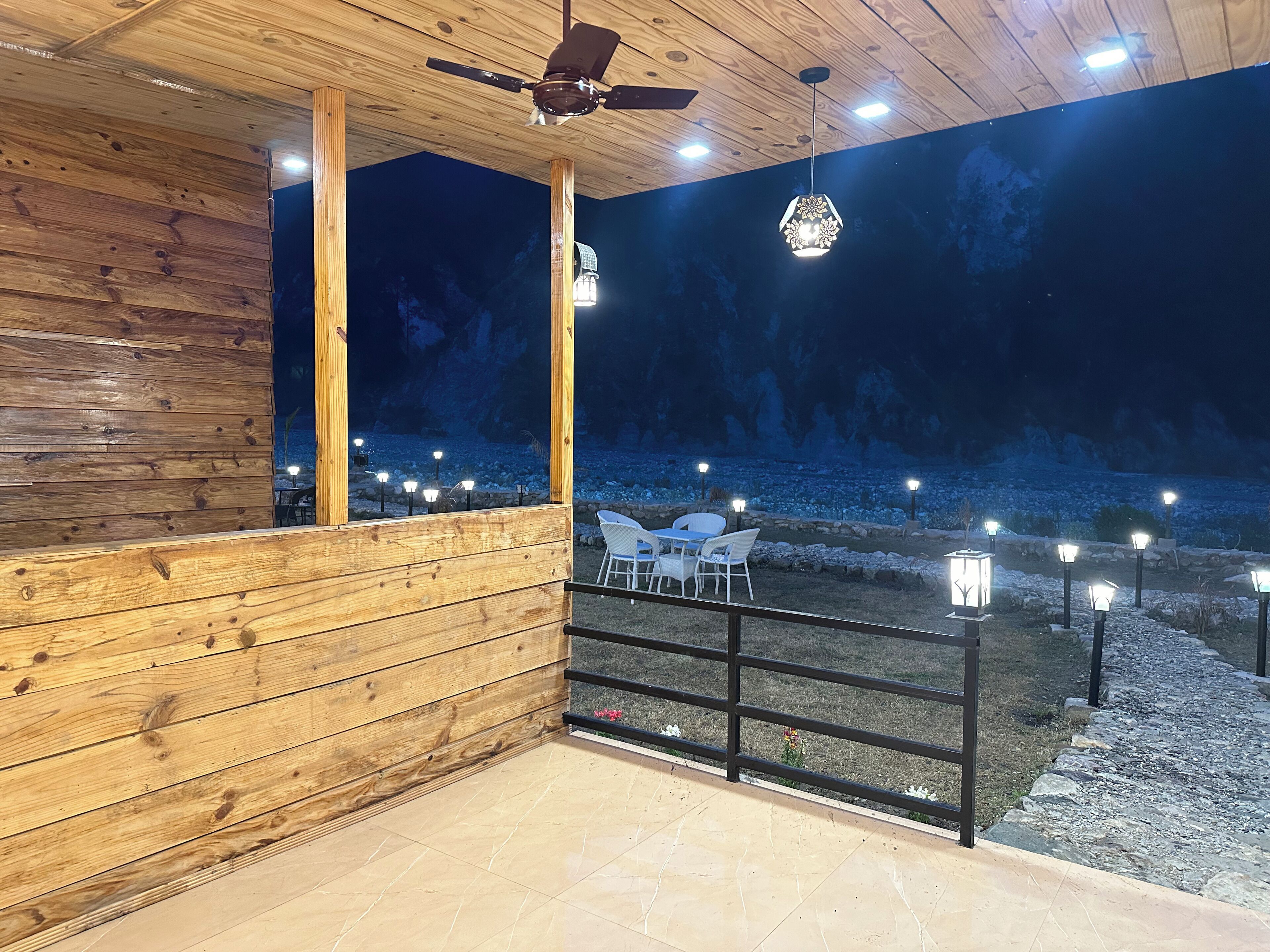Interior de madera con balcón que da a un paisaje rocoso de noche.