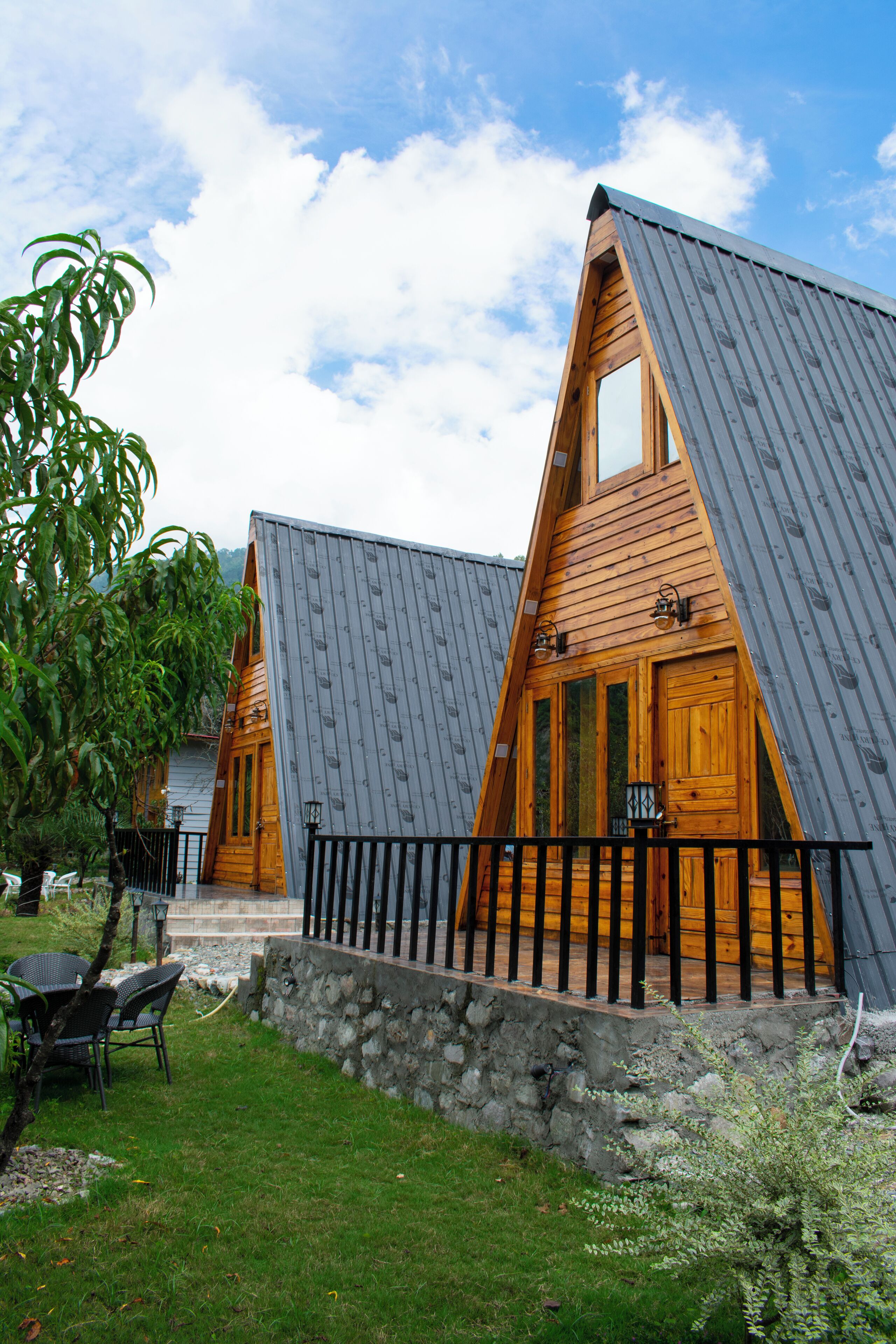 A row of wooden cabins with sloped roofs and a stone pathway leading to the entrance.