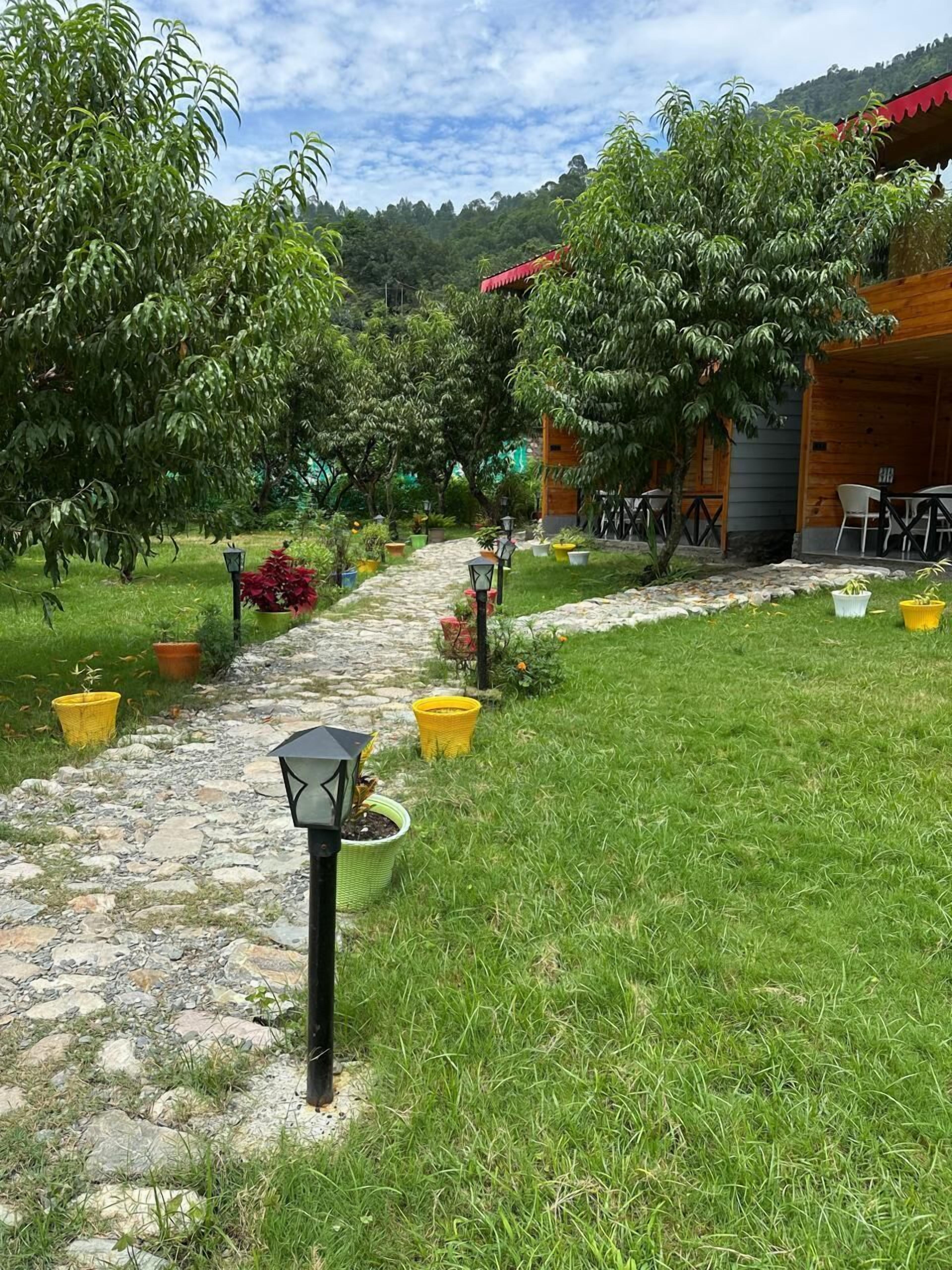 Un sendero en un jardín que lleva a una construcción de madera con asientos al aire libre.