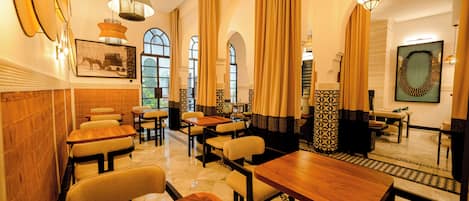 A restaurant with wooden tables and chairs, large windows, and decorative lighting.