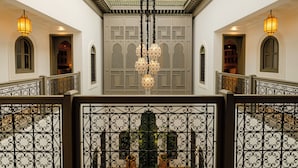 Un intérieur somptueux, avec un plafond haut, des balustrades en fer forgé richement décorées et un lustre central.