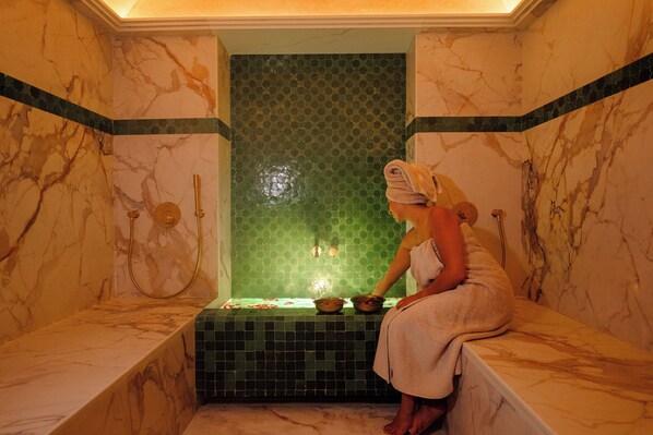 A marble bathroom with a bathtub, a green mosaic wall, and a towel on the edge. - Door Janna (Marrakech)