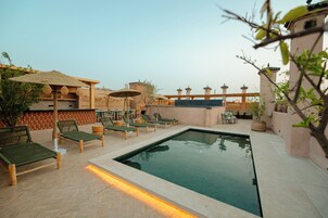 Una piscina al aire libre, sombrillas, sillones reclinables de piscina