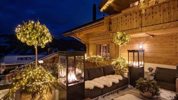 A cozy chalet with a fireplace, plush seating, and a snow-covered deck. - Spacious Chalet With Private Pool (Saanen)