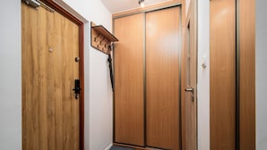 A hallway with wooden doors, a coat rack, and a mat at the entrance. - Apartamenty Sun & Snow Kasprowicza Warszawa (Warsaw)