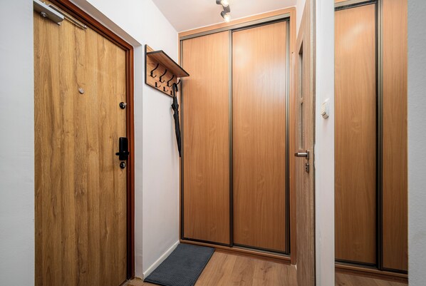 A hallway with wooden doors, a coat rack, and a mat at the entrance. - Apartamenty Sun & Snow Kasprowicza Warszawa (Warsaw)