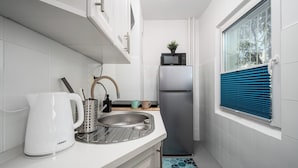 A compact kitchen with white tiles, a stainless steel sink, a kettle, a toaster, and a refrigerator. - Apartamenty Sun & Snow Kasprowicza Warszawa (Warsaw)