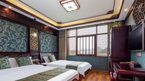 A hotel room with two beds, a TV, a desk, and a window with decorative lattice. - Siximingyuan in Wuyuan (Wuyuan)