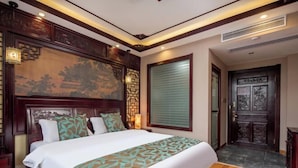 A hotel room with a large bed, wooden headboard, and a traditional Chinese-style wall painting. - Siximingyuan in Wuyuan (Wuyuan)
