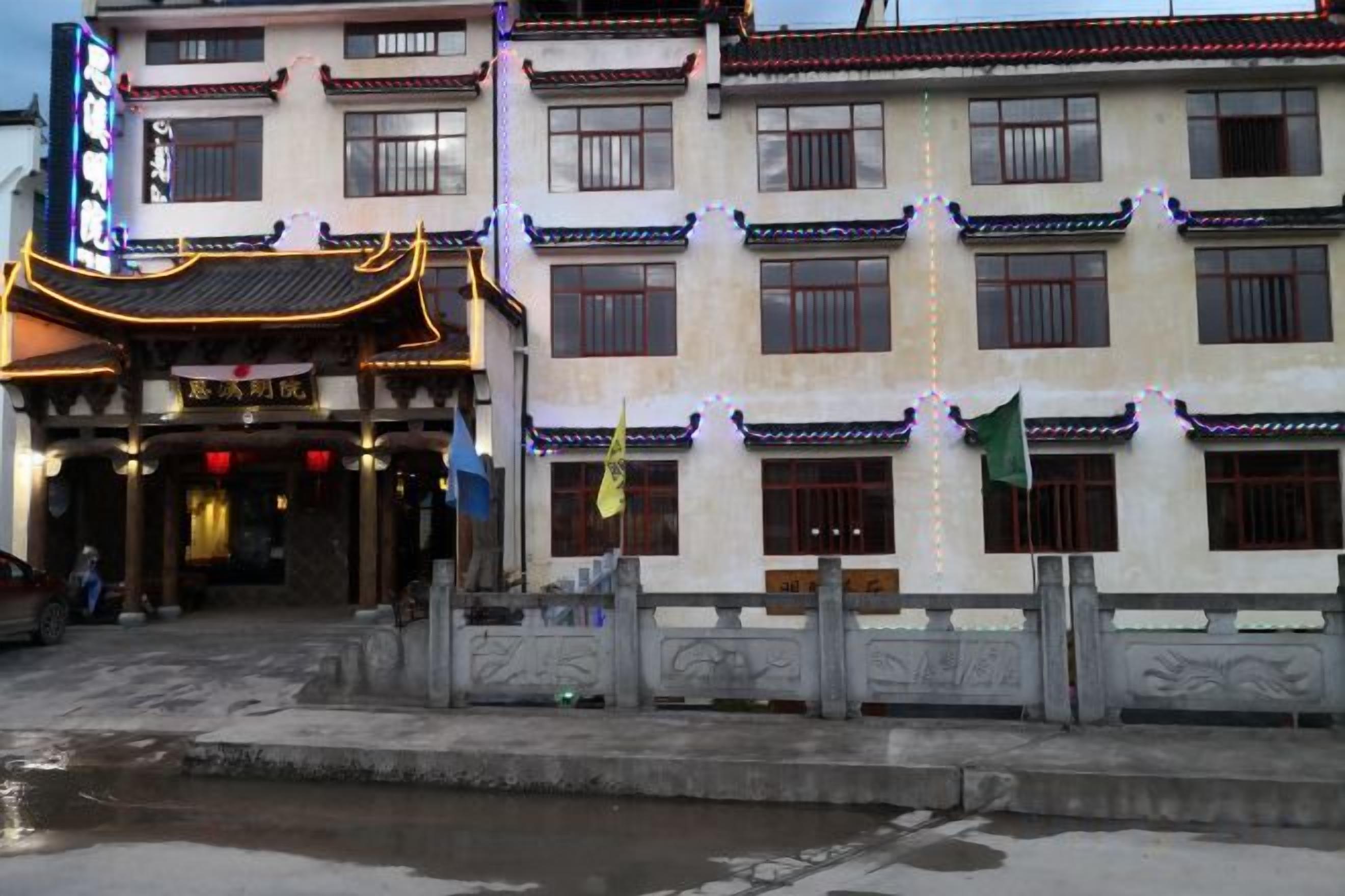 A traditional multi-story building with a tiled roof, a covered entrance, and a small courtyard.