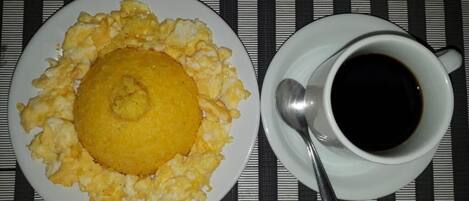 Un plato de huevos revueltos y una taza de café negro sobre un mantel a rayas.