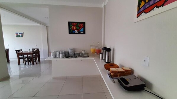 A clean, modern kitchen with a dining area, white walls, and a tiled floor. - Pousada Brilho dos Lençóis (Barreirinhas)