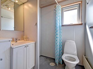 A compact bathroom with a white sink, a toilet, and a shower curtain with blue polka dots. - 4 Person Holiday Park Home in Jelling (Jelling)
