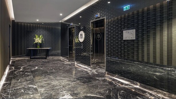 Eine moderne Lobby mit Marmorboden, einer Rezeption und einem wandmontierten Aufzug.
