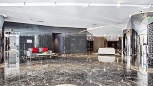 Eine moderne Lobby mit Marmorboden, einer Couch mit roten Kissen und einer Wand mit Muster.