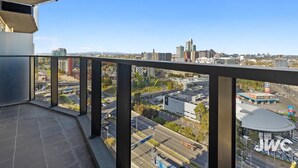 Ein Balkon mit freiem Blick auf eine Stadtlandschaft, darunter Gebäude und Straßen.
