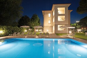 Ein modernes Hotel mit Schwimmbad, Liegestühlen und Sonnenschirmen.