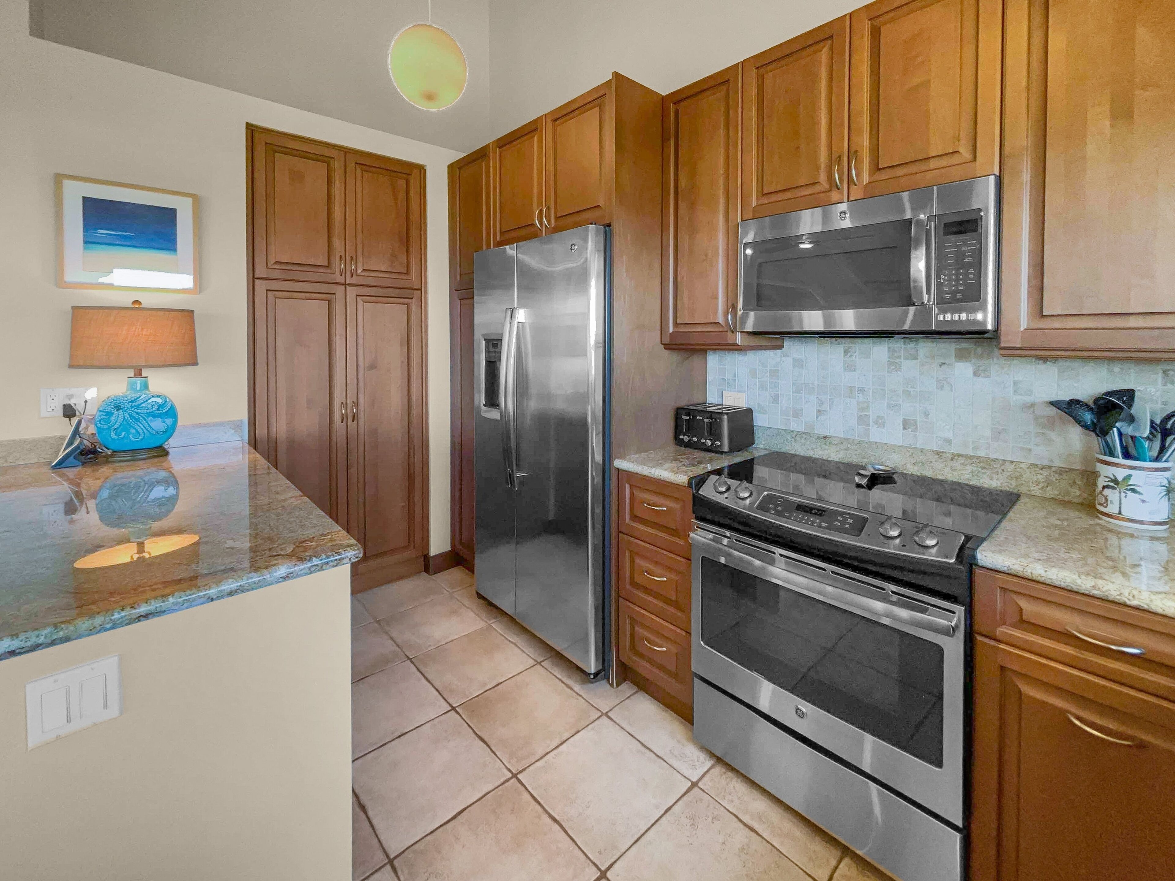 A kitchen with wooden cabinets, stainless steel appliances, and a tiled backsplash.