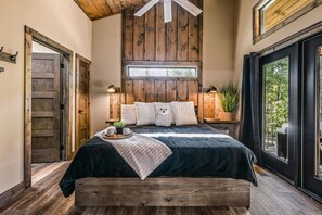 Une chambre à coucher avec un lit, des murs en bois, une fenêtre et une vue sur l’extérieur.