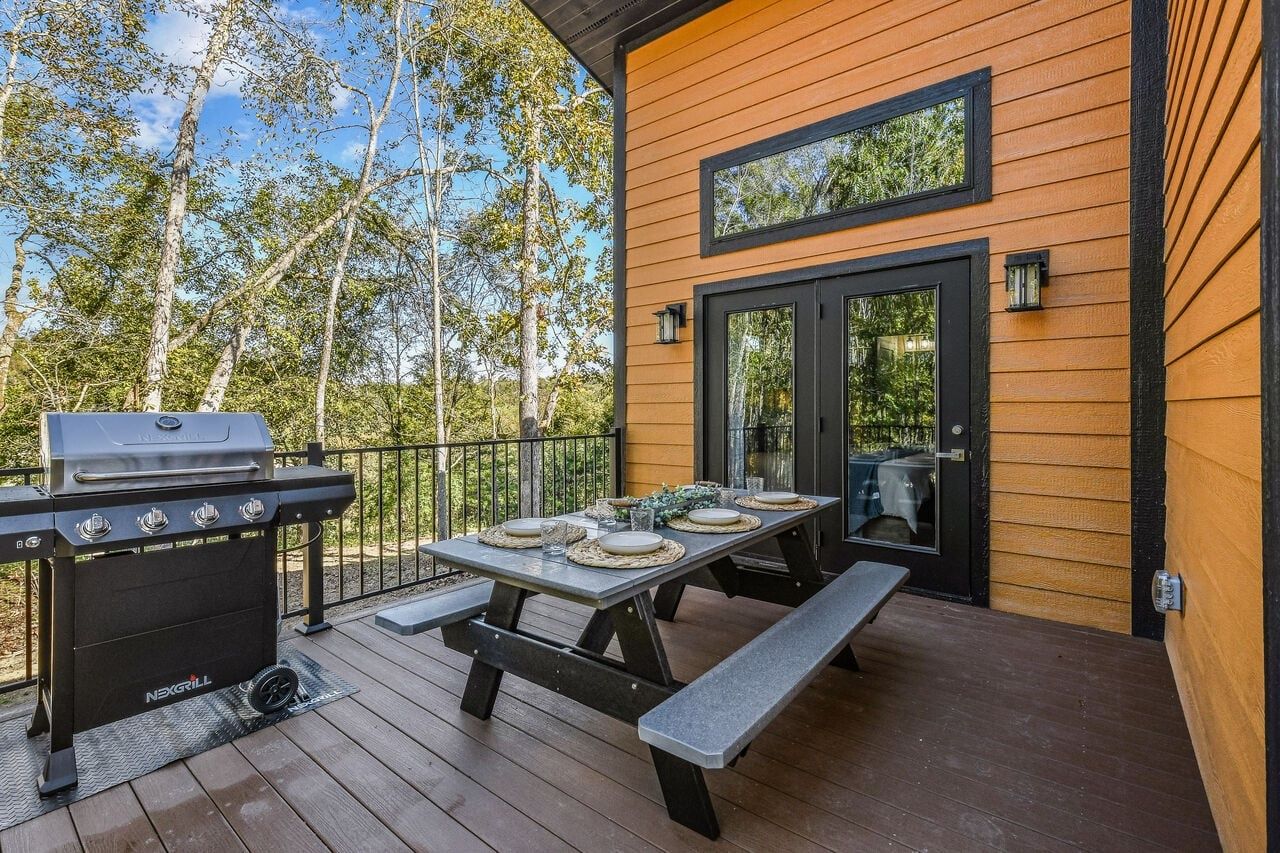 Una terraza al aire libre con una parrilla, una mesa de picnic y una puerta con ventanal.