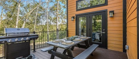 Una terraza al aire libre con una parrilla, una mesa de picnic y una puerta con ventanal.