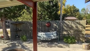 Un espacio al aire libre techado, con piso de concreto, cerca de madera y un hogar para fuego.