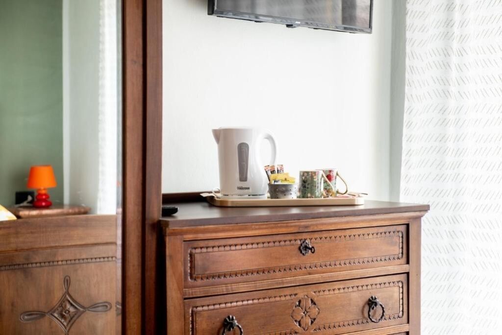 Une commode en bois avec deux tiroirs, et un téléviseur fixé au mur au-dessus.