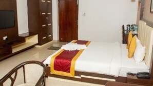 Una habitación de hotel con cama, televisor, armario y escritorio con lámpara.
