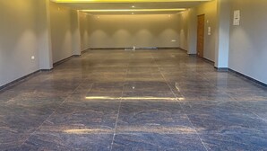 A spacious, well-lit hallway with a dark tiled floor and recessed lighting. - Pinky Hotel (Dausa)