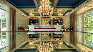 Een luxueuze kamer met een centraal gelegen reflectievijver, weelderige kroonluchters en symmetrische designelementen.
