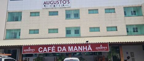 A hotel with a sign for 'AUGUSTO'S HOTEL' and a cafe named 'CAFÉ DA MANHÃ'.